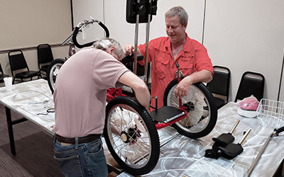men working on therapeutic tricycles over a table